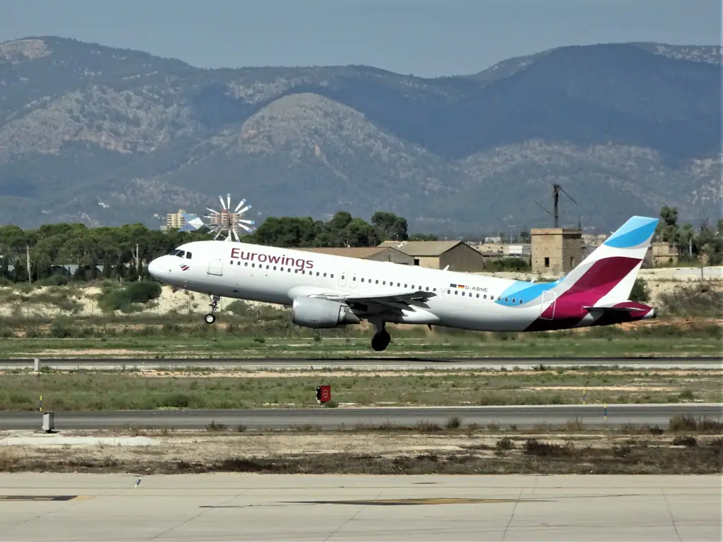 Un avion décolle de l’aéroport de Palma, devant un moulin à vent et les montagnes de Majorque
