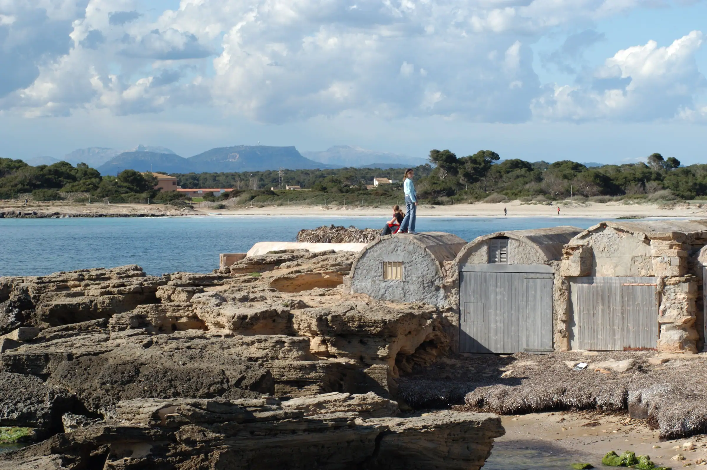 Abris de bateaux traditionnels sur les rochers d’es Dolç, à la Colònia de Sant Jordi, avec la plage en arrière-plan
