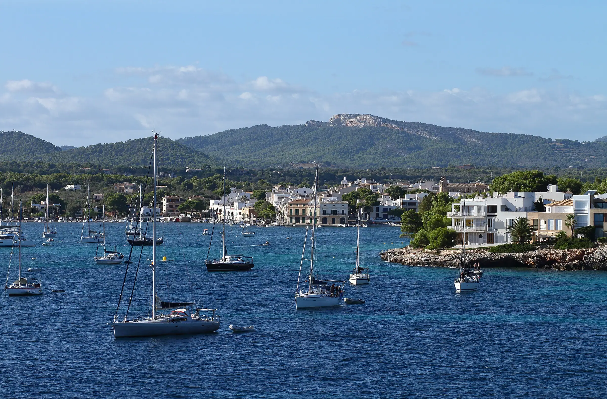 Voiliers au mouillage dans la baie de Portocolom, devant les maisons blanches et les collines