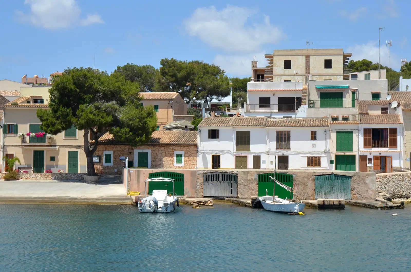 Maisons blanches et cales à bateaux au bord du port de Porto Petro