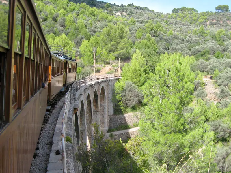 Le train en bois de Sóller longe un viaduc de pierre au milieu des pins