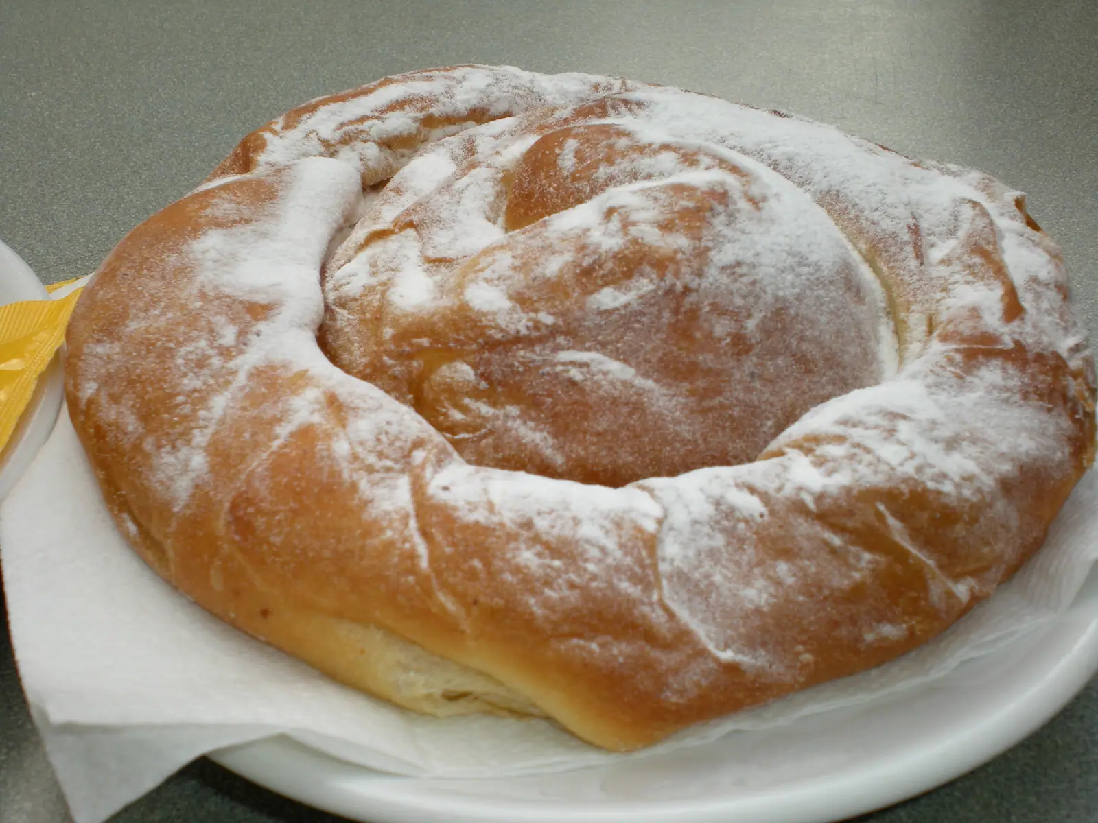 Une ensaïmada en spirale saupoudrée de sucre glace, sur une assiette