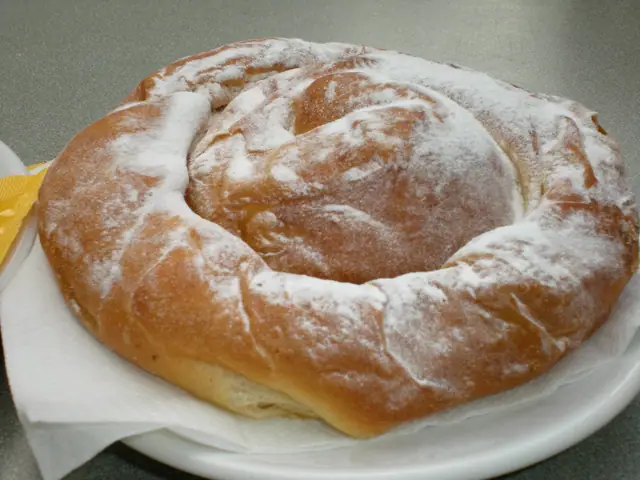 Une ensaïmada en spirale saupoudrée de sucre glace, sur une assiette