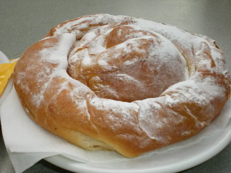Une ensaïmada en spirale saupoudrée de sucre glace, sur une assiette