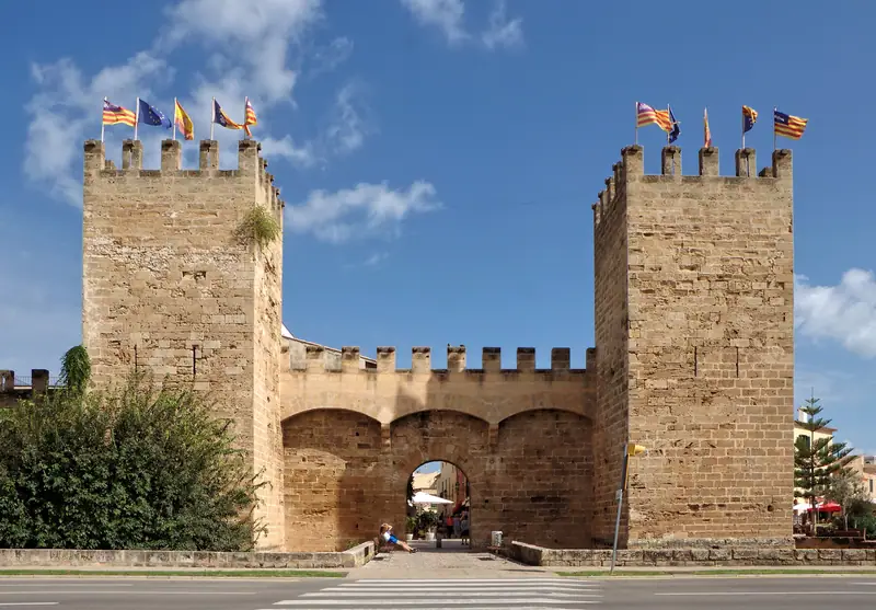 La porte fortifiée des remparts d'Alcúdia, deux tours crénelées sous le ciel bleu