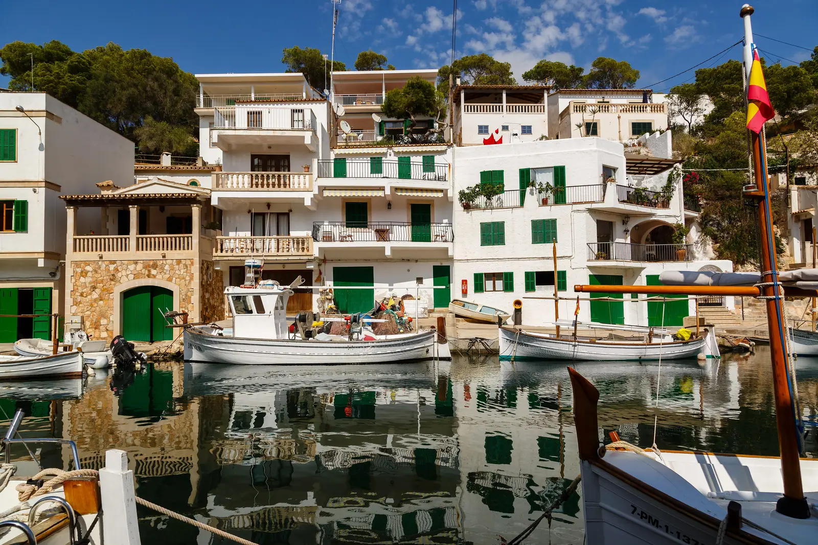 Les maisons blanches aux volets verts du port de Cala Figuera, barques amarrées
