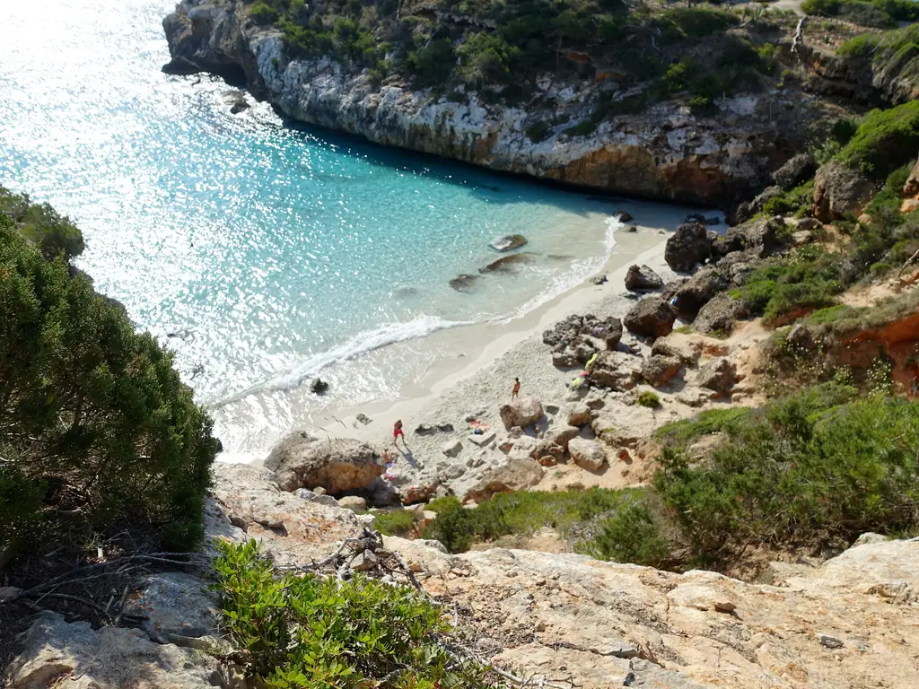 La crique de Caló des Moro, eau turquoise et sable clair entre des rochers boisés