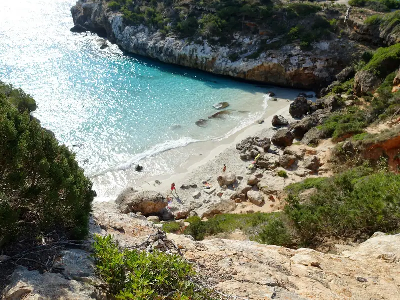 La crique de Caló des Moro, eau turquoise et sable clair entre des rochers boisés