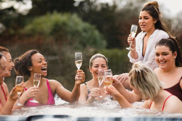 Un groupe d'amies trinquant au champagne et riant dans le jacuzzi de leur villa de location lors d'un week-end EVJF à Majorque.