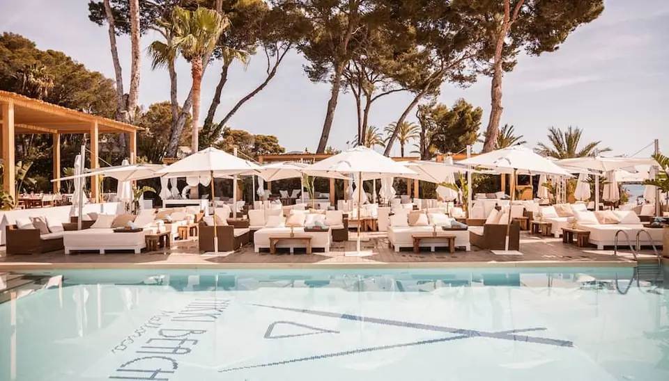 Vue sur la piscine et les lits blancs du Nikki Beach Majorque à Magaluf, idéal pour un EVJF de luxe.
