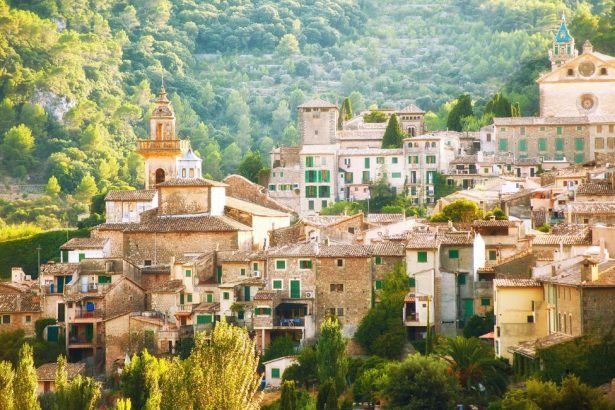 Vue panoramique du village de Valldemossa niché dans la Serra de Tramuntana, avec ses maisons en pierre et le clocher turquoise de la Chartreuse qui domine la vallée