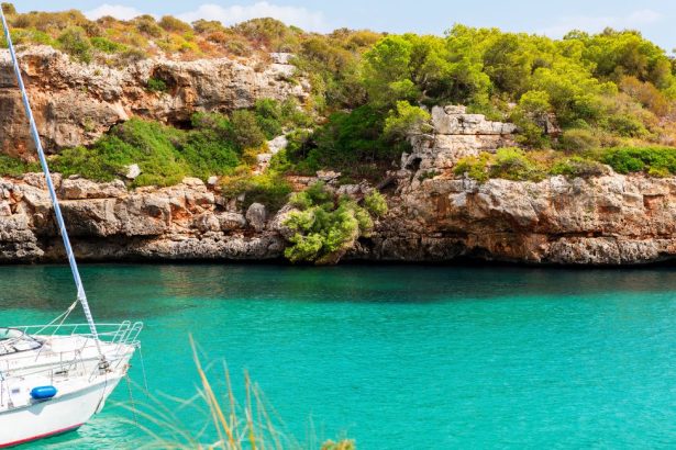 Voilier dans une crique aux eaux turquoise bordée de falaises rocheuses à Cala Sa Nau à Majorque