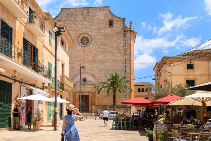 Place animée de Santanyí avec église en pierre, terrasses et bâtiments en calcaire à Majorque