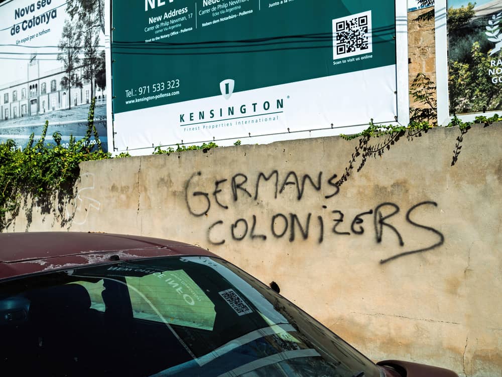 Graffiti « Germans Colonizers » sur un mur à Majorque illustrant les tensions liées à la présence allemande sur l’île.