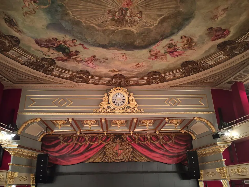 Photo : Joan Gené, CC BY-SA 4.0, via Wikimedia Commons Le rideau de scène et l'horloge dorée du Teatre Principal de Palma